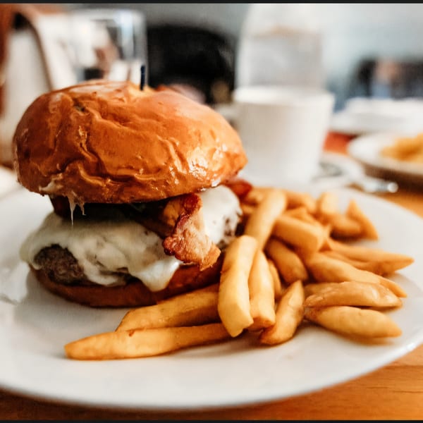 A Watermark of Wading River burger with melted cheese and bacon, served with golden fries.