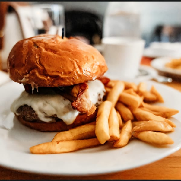 A juicy burger with melted cheese and bacon, served with a side of golden french fries.